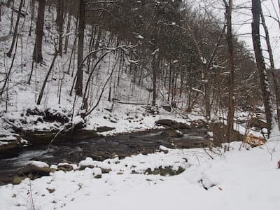 Snow on a mountain with a river flowing through.