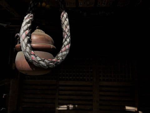 A Japanese Buddhist temple bell and a rope in front of a black background